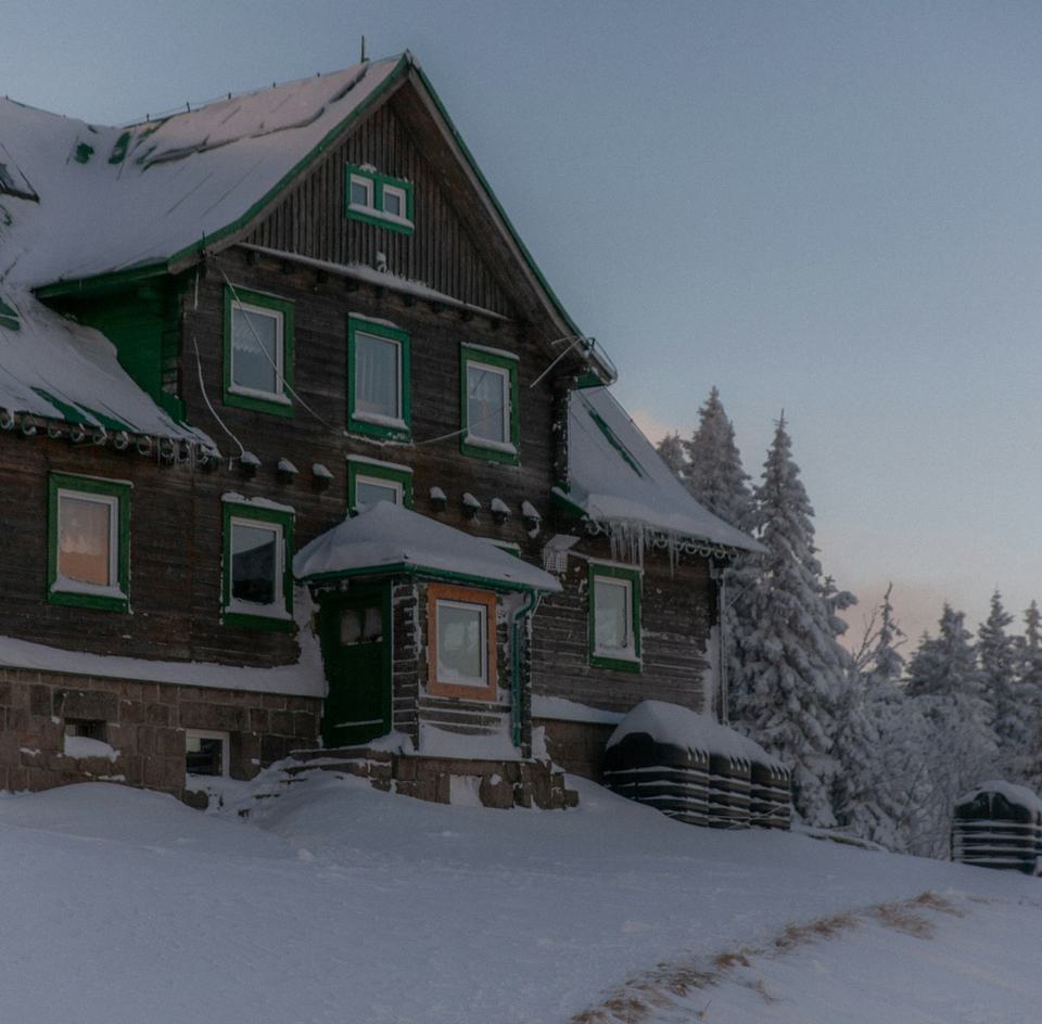 A snow-covered house with every window lit during a winter evening